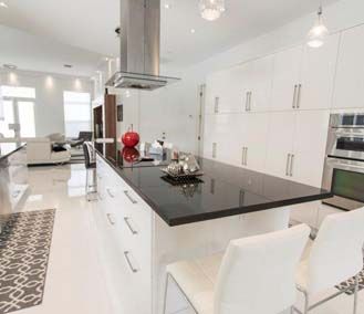 A kitchen with white cabinets , black counter tops , and stainless steel appliances.
