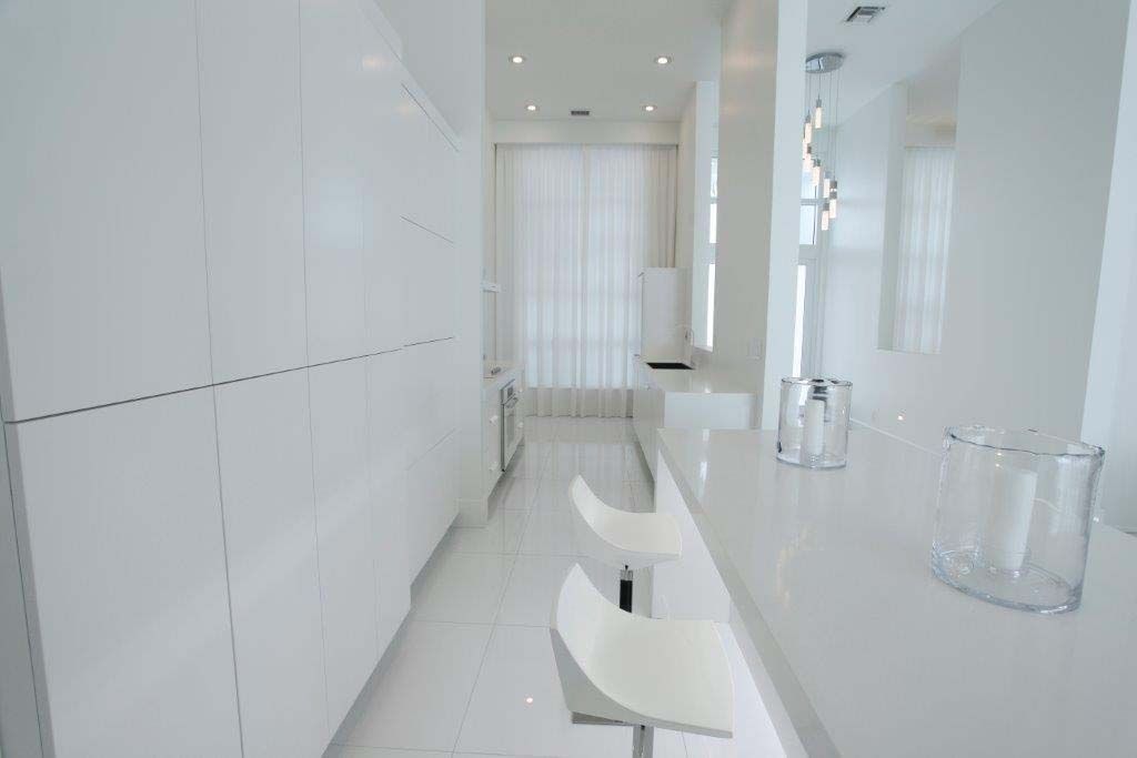 A white kitchen with a long counter and two bar stools.