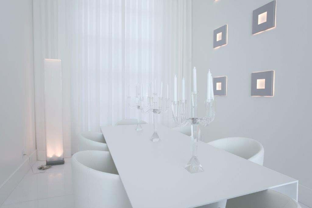 A dining room with a long white table and chairs.