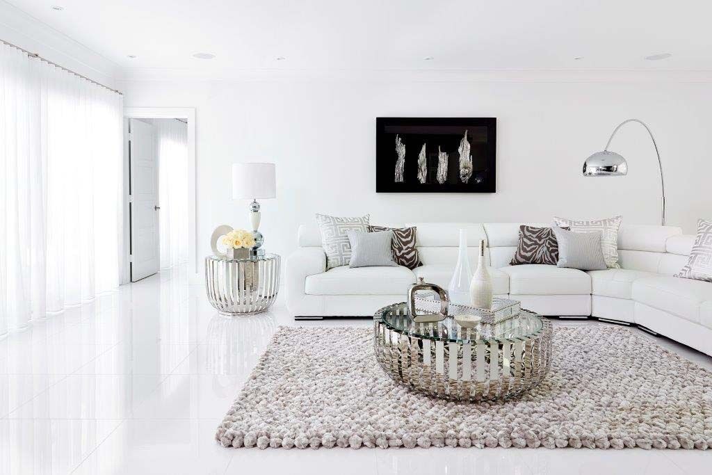 A living room with a white couch , a coffee table , and a rug.