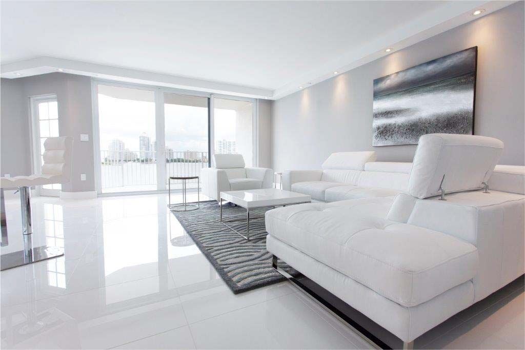 A living room with white furniture and a large window.