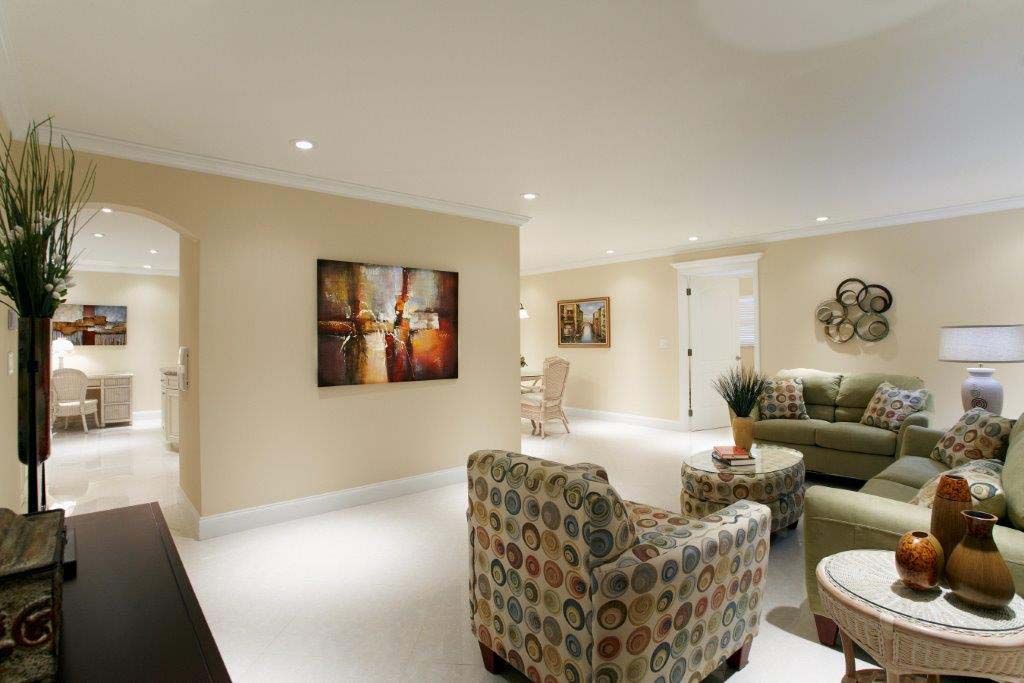 A living room with a couch , chairs , tables and a painting on the wall.