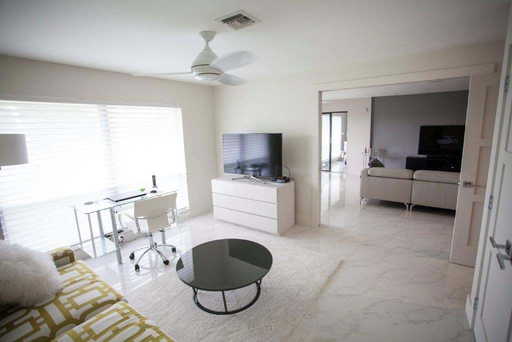 A living room with a couch , table , television and ceiling fan.