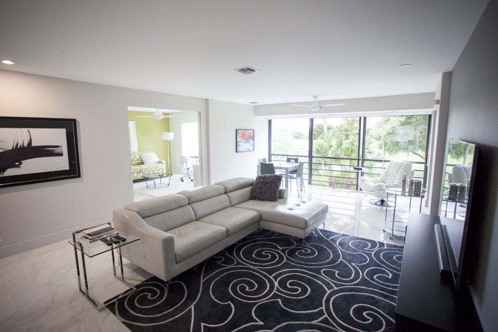 A living room with a white couch and a black and white rug.