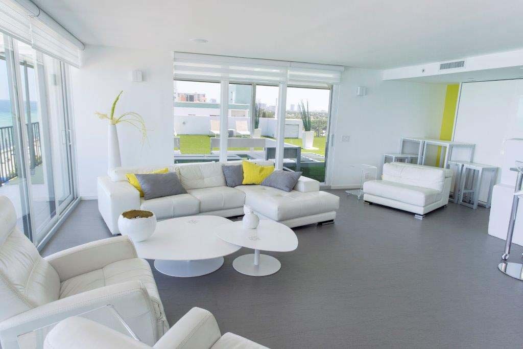 A living room with a couch , chairs , tables and a balcony.