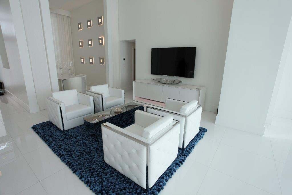 A living room with white furniture and a flat screen tv.