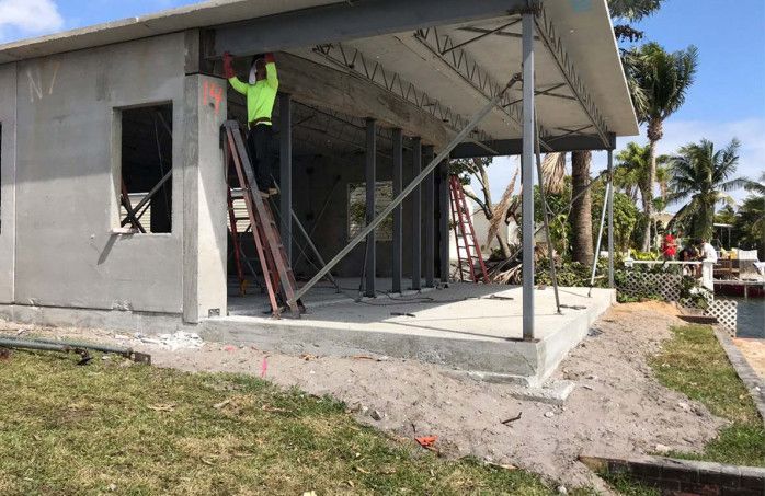 A man is standing on a ladder in front of a house under construction.