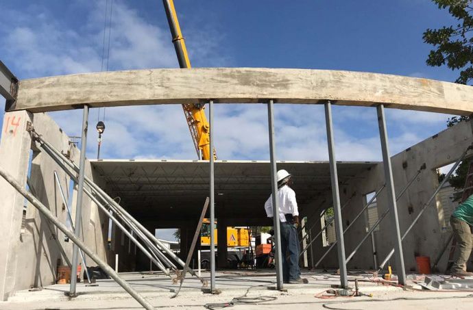 A crane is lifting a wooden beam into a building under construction