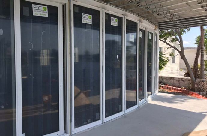 A row of sliding glass doors are being installed on a porch.