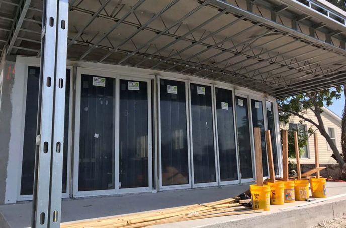 A building under construction with buckets and shovels in front of it.
