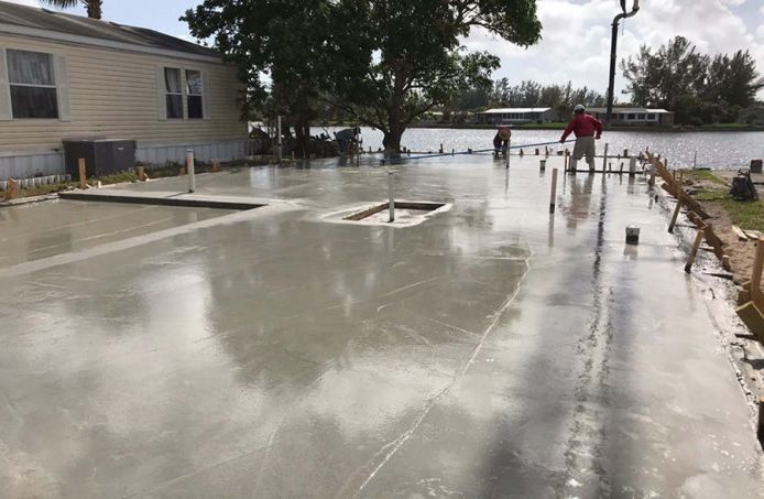 A man is working on a concrete driveway in front of a house.