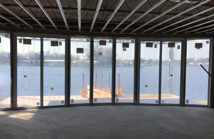 A room with a lot of windows overlooking a body of water.