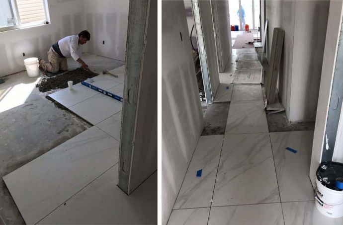 A man is laying tile on the floor of a room.