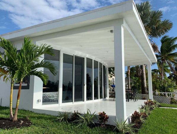 A white house with a lot of windows and palm trees in front of it