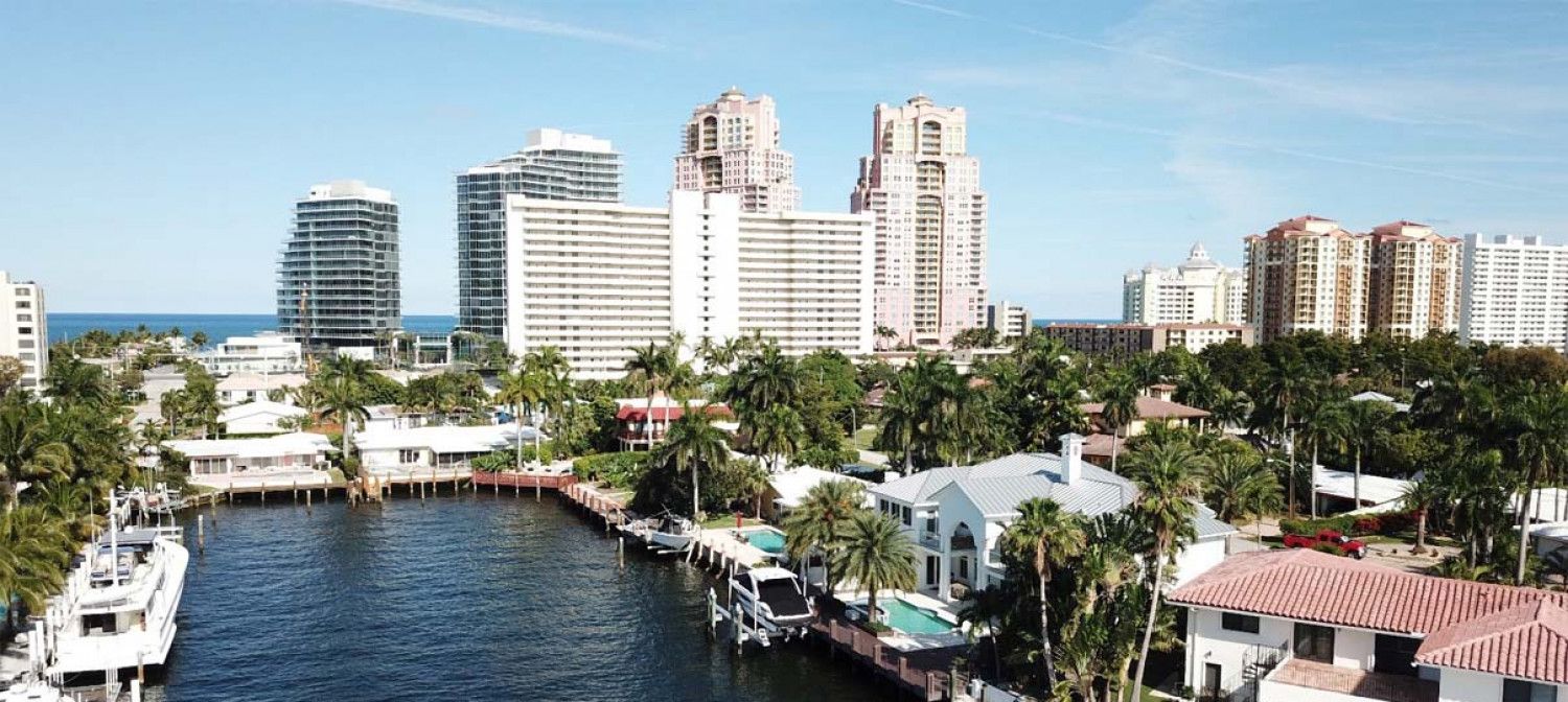 An aerial view of a city with a body of water surrounded by buildings and trees.