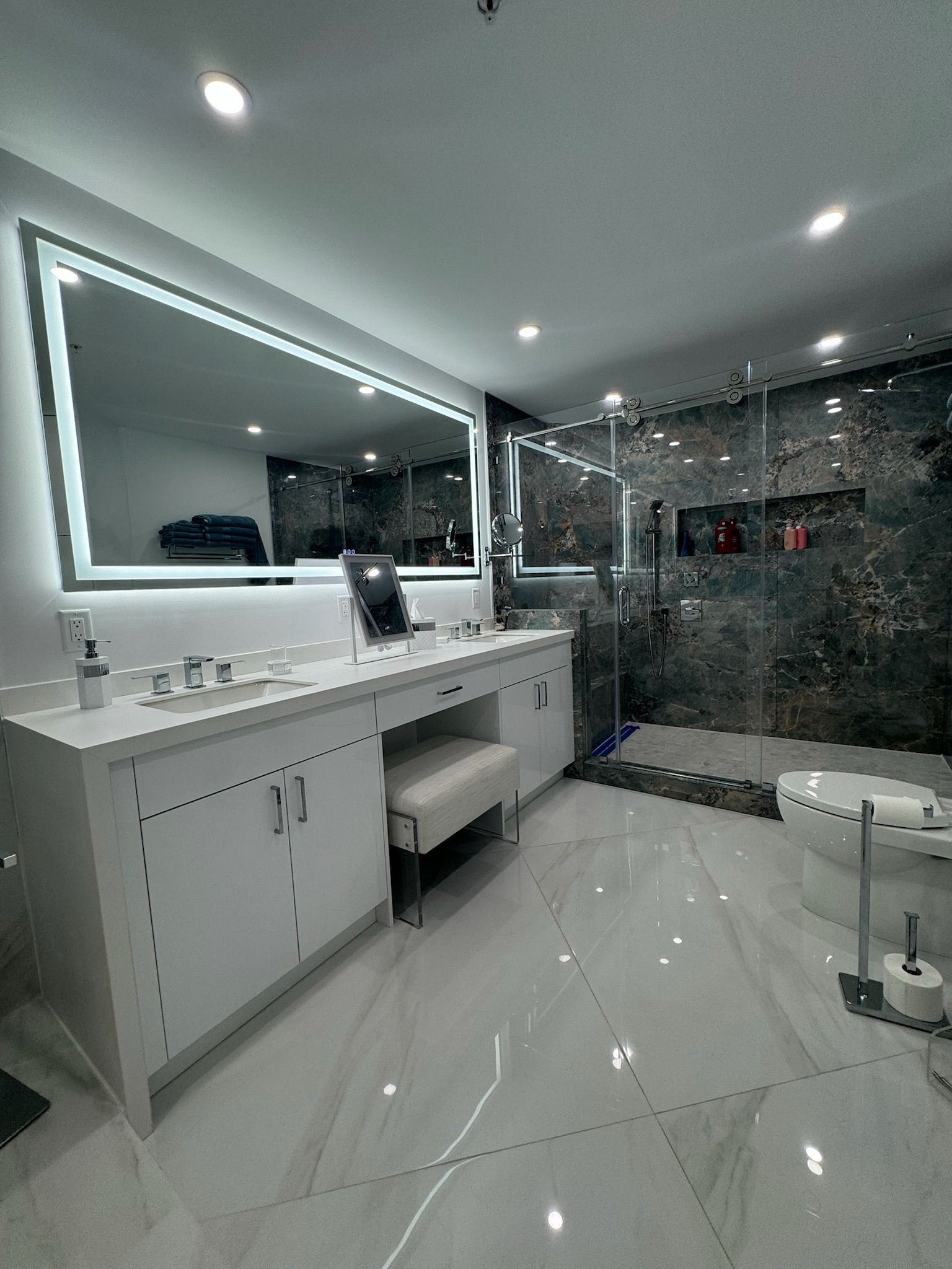 A bathroom with two sinks , a large mirror and a walk in shower.