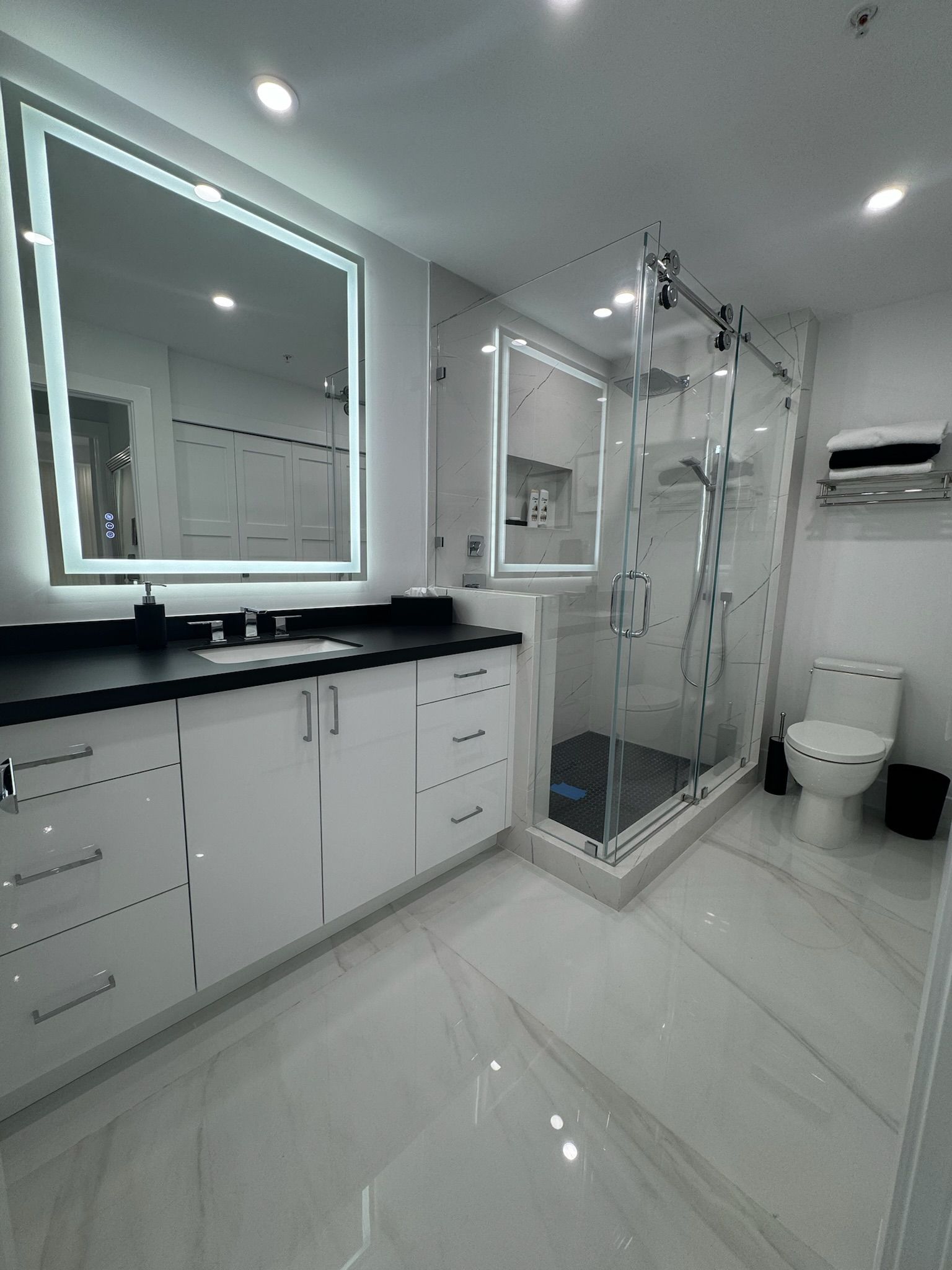A bathroom with a toilet , sink , mirror and shower.