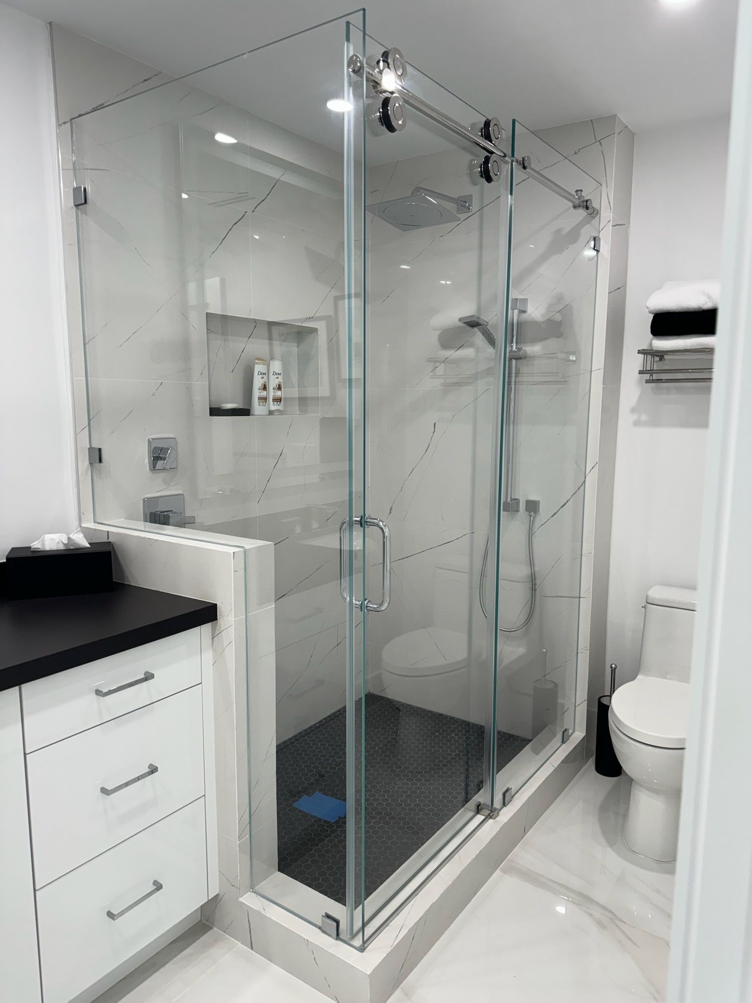 A bathroom with a toilet , sink , shower and glass door.