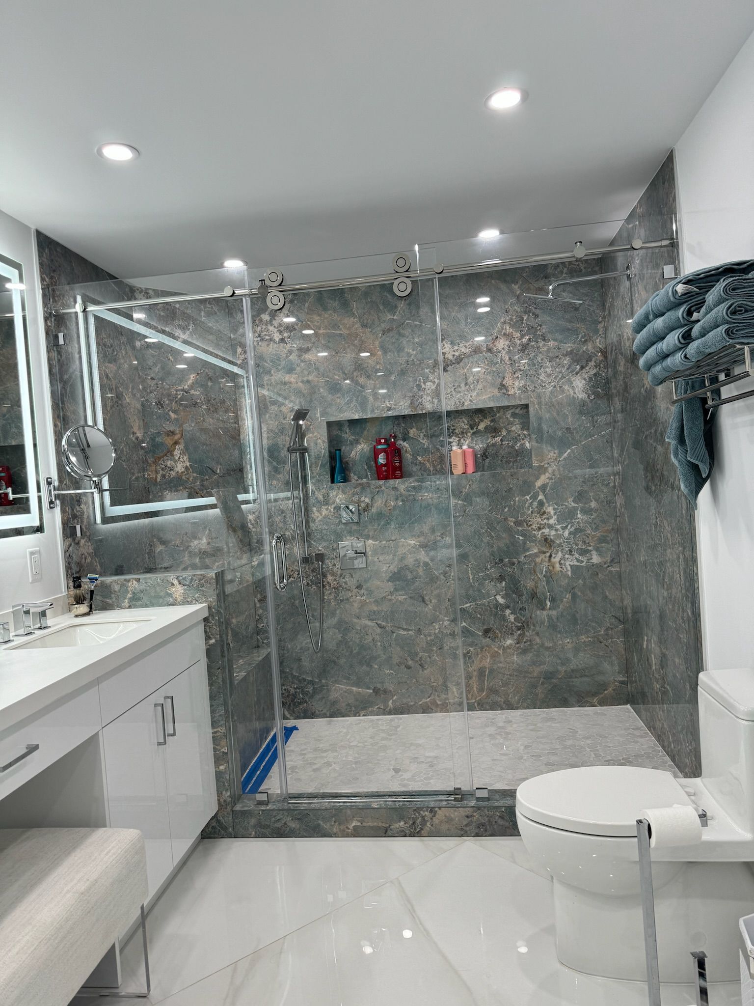 A bathroom with a walk in shower , toilet , sink and mirror.