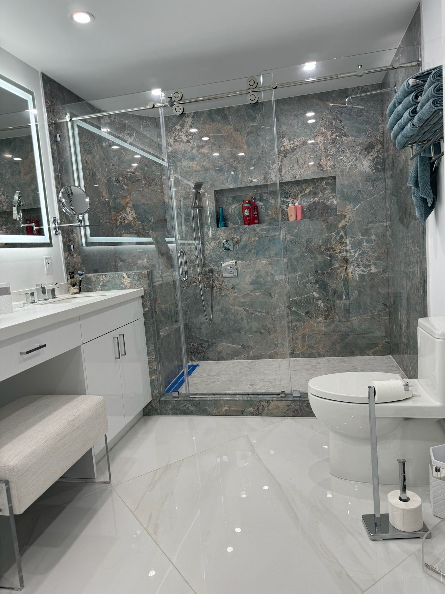 A bathroom with a toilet , sink , mirror and walk in shower.