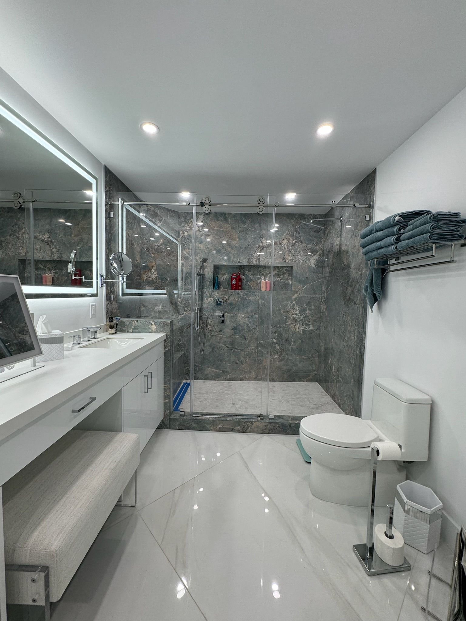 A bathroom with a toilet , sink , mirror and walk in shower.