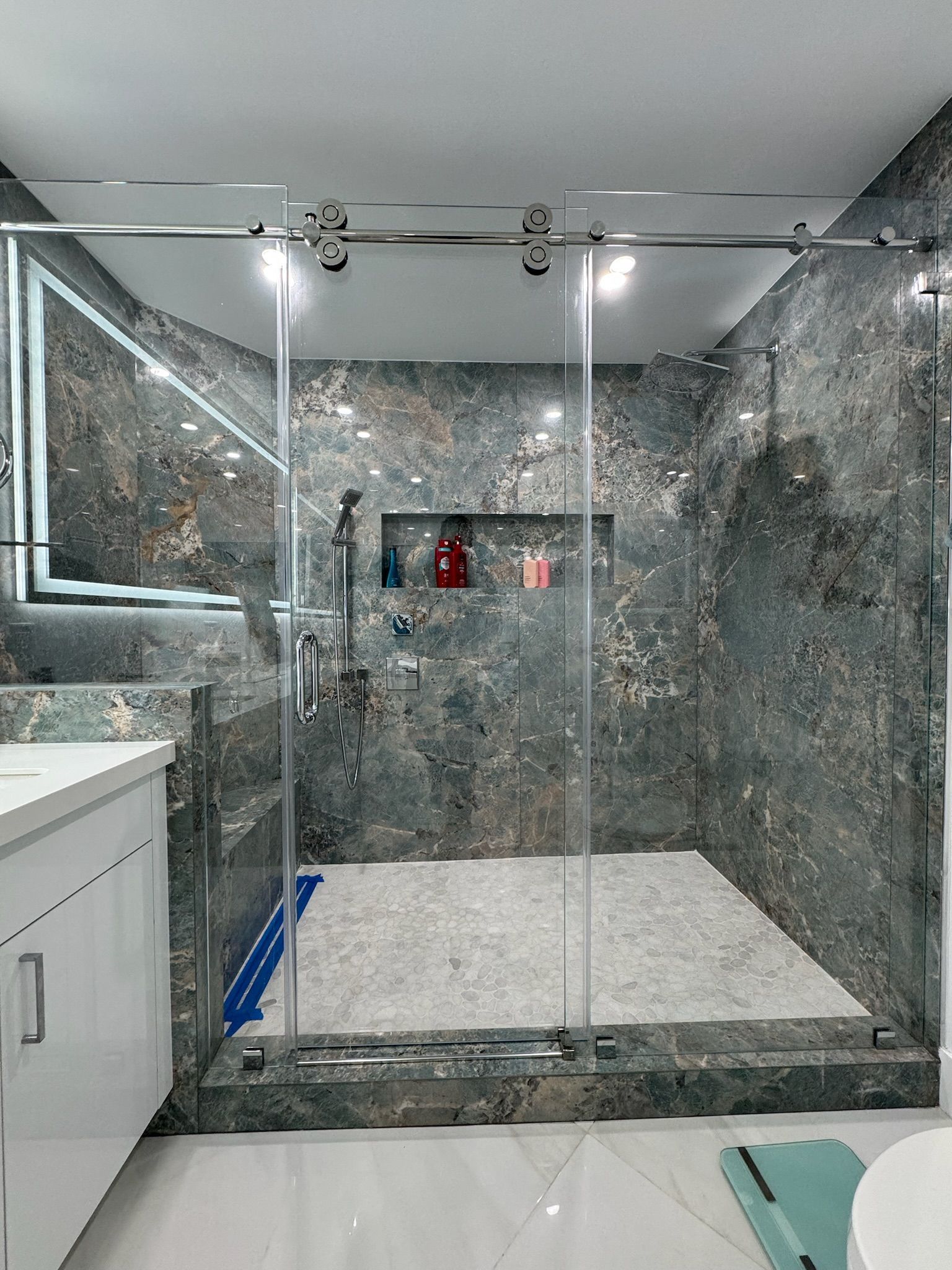 A bathroom with a walk in shower with sliding glass doors.