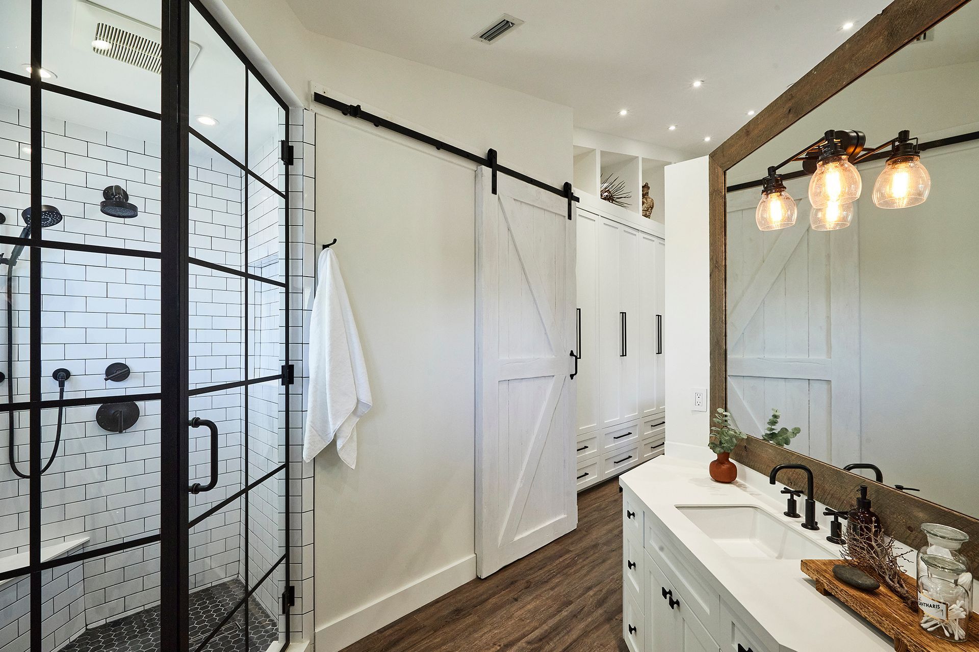 A bathroom with sliding barn doors , a sink , and a mirror.