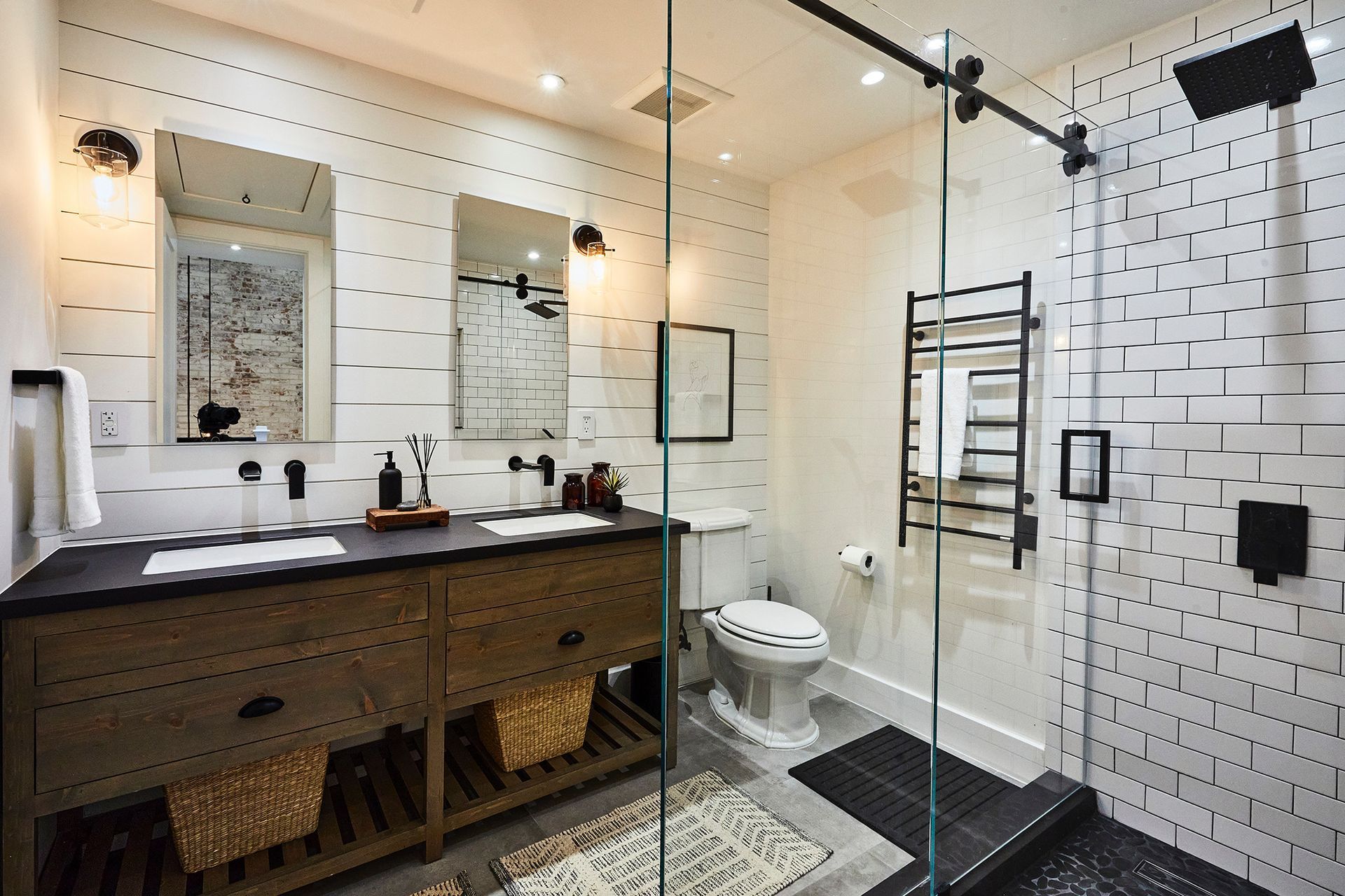 A bathroom with two sinks , a toilet , and a walk in shower.