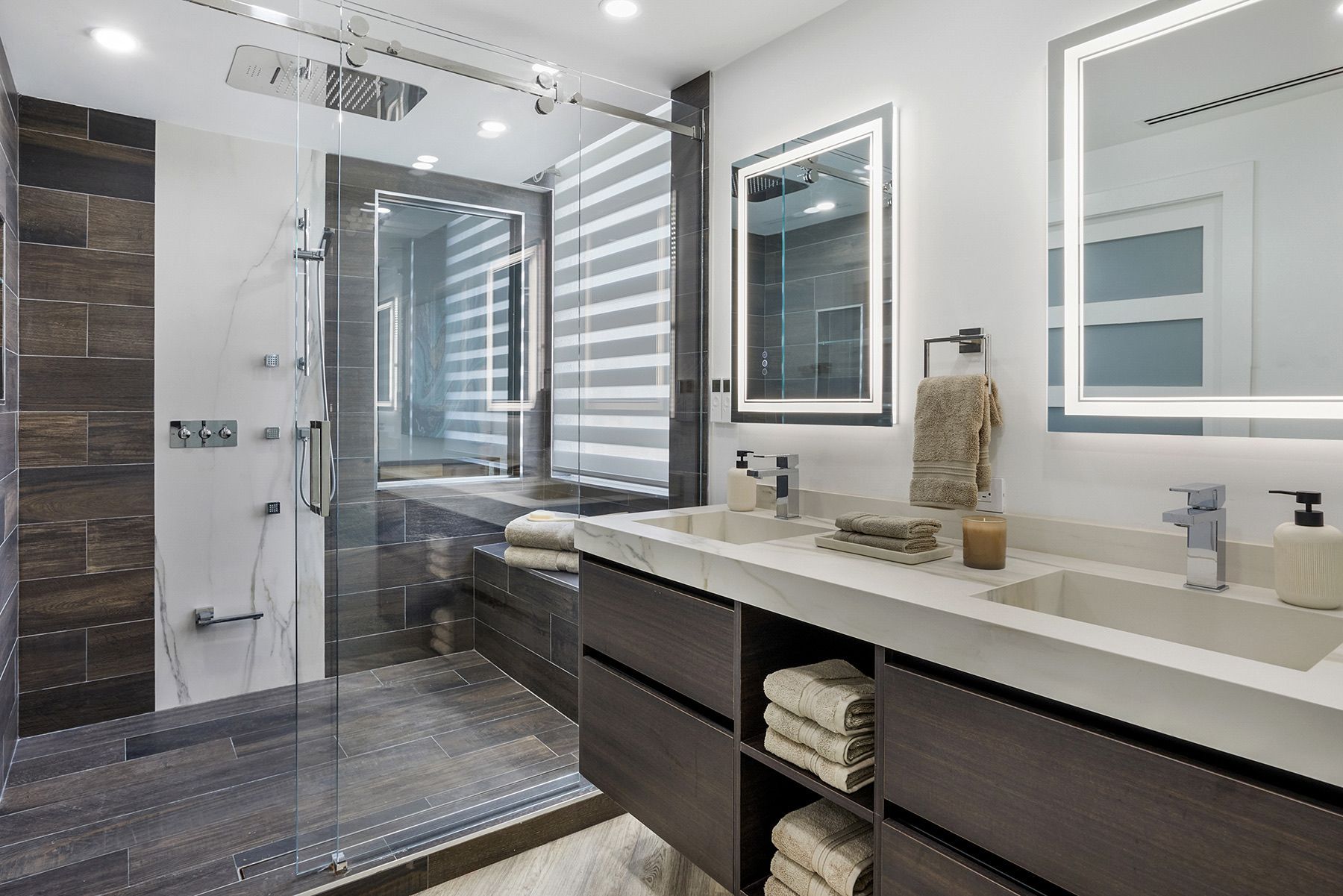 A bathroom with two sinks and a walk in shower.