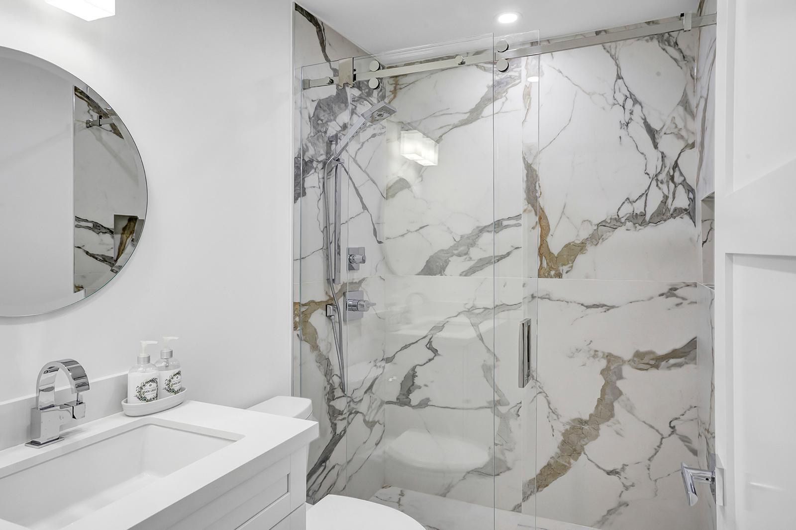 A bathroom with a sink , toilet , shower and mirror.