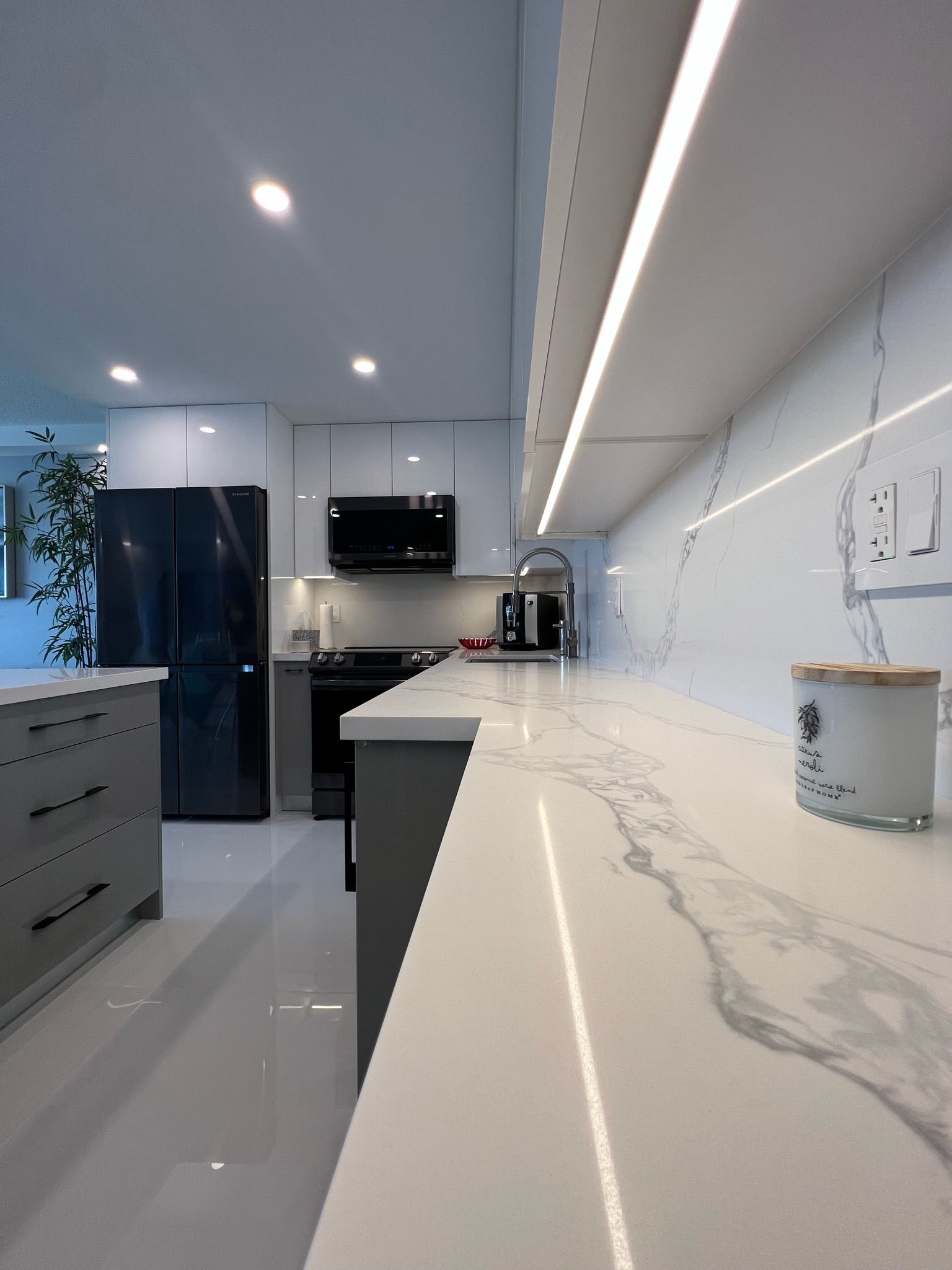 A kitchen with a marble counter top and a black refrigerator.