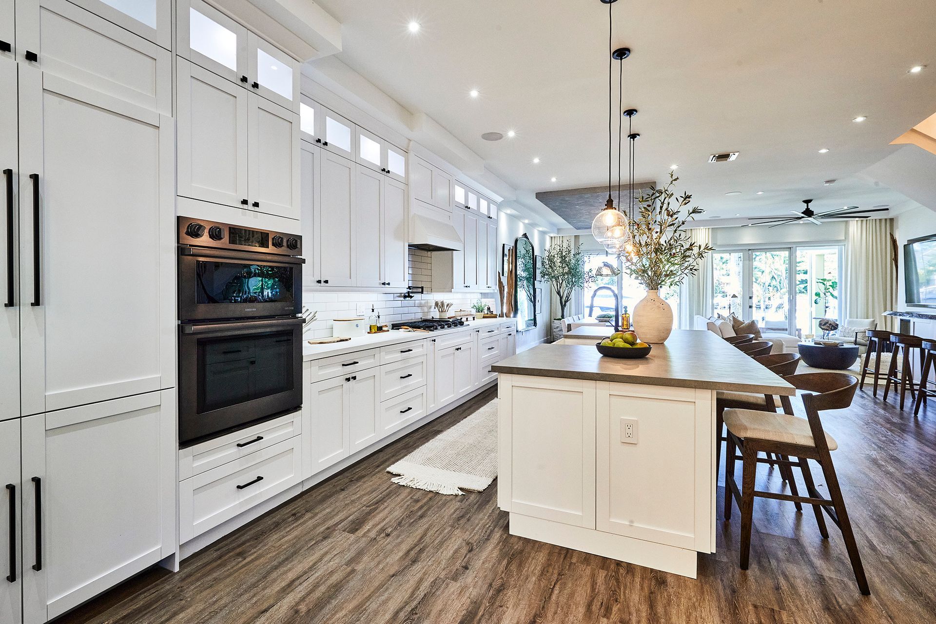 A kitchen with white cabinets , black appliances , and a large island.