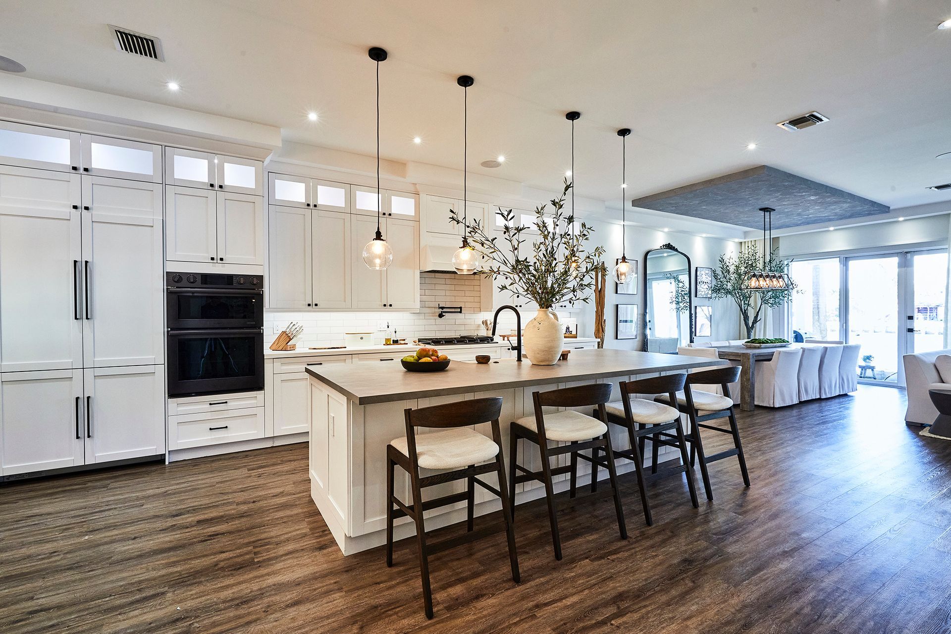 A kitchen with white cabinets , a large island , and wooden floors.