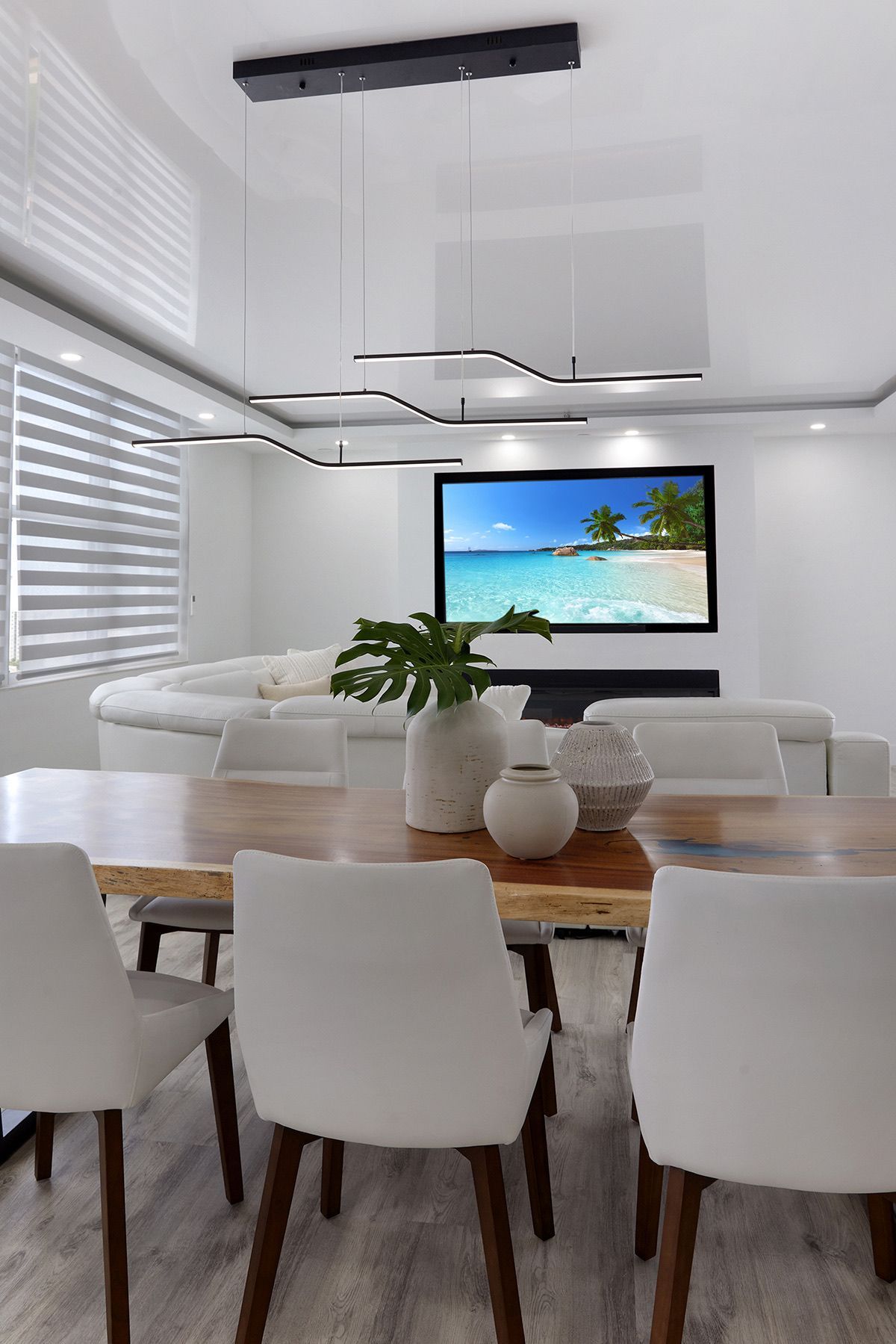 A dining room with a table and chairs and a television on the wall.