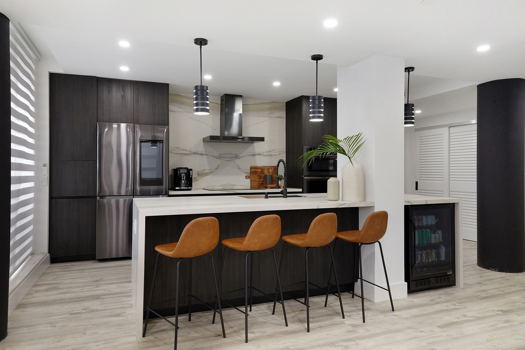 A kitchen with stools and a refrigerator in it