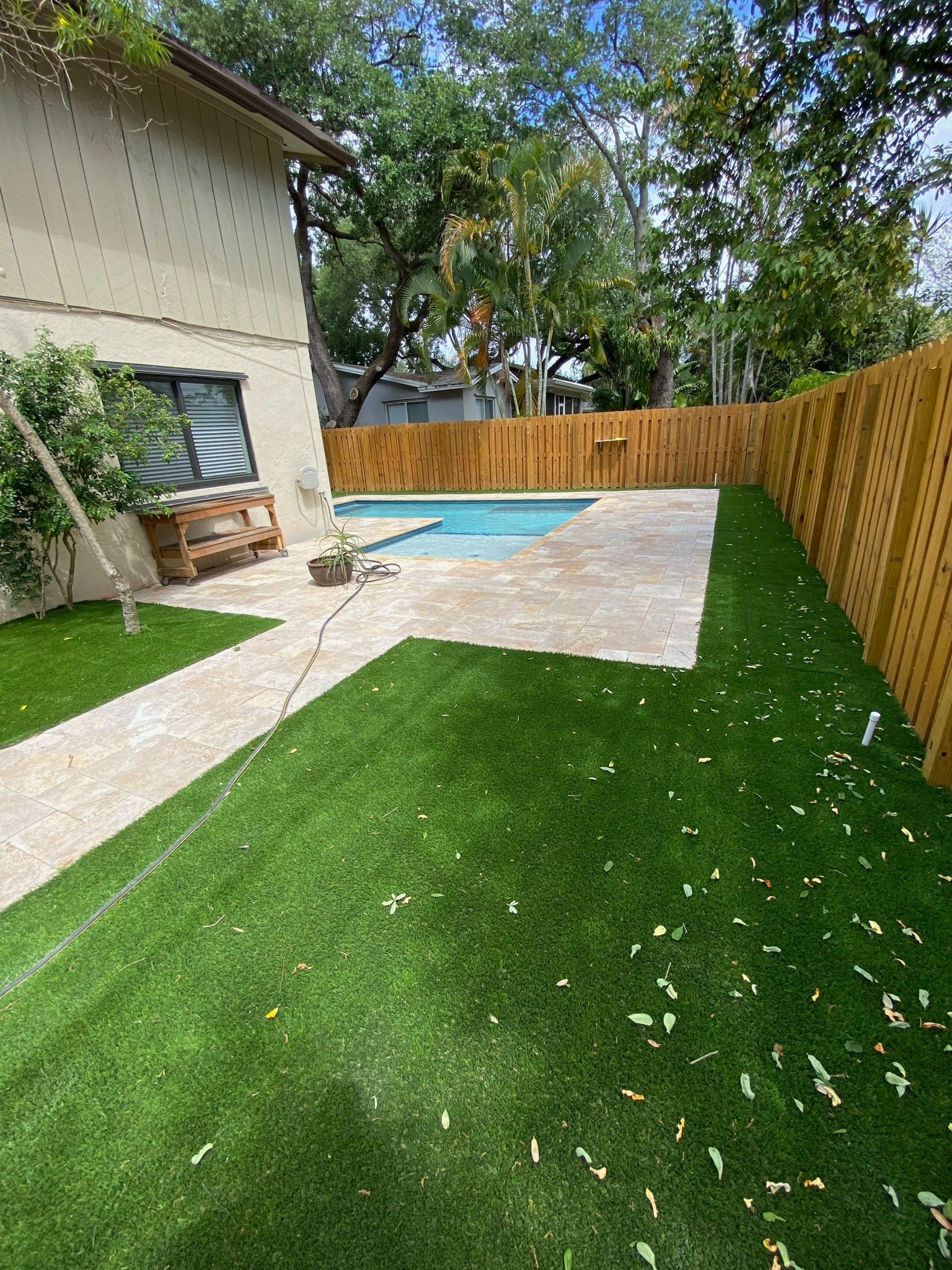 A backyard with a wooden fence and a swimming pool.