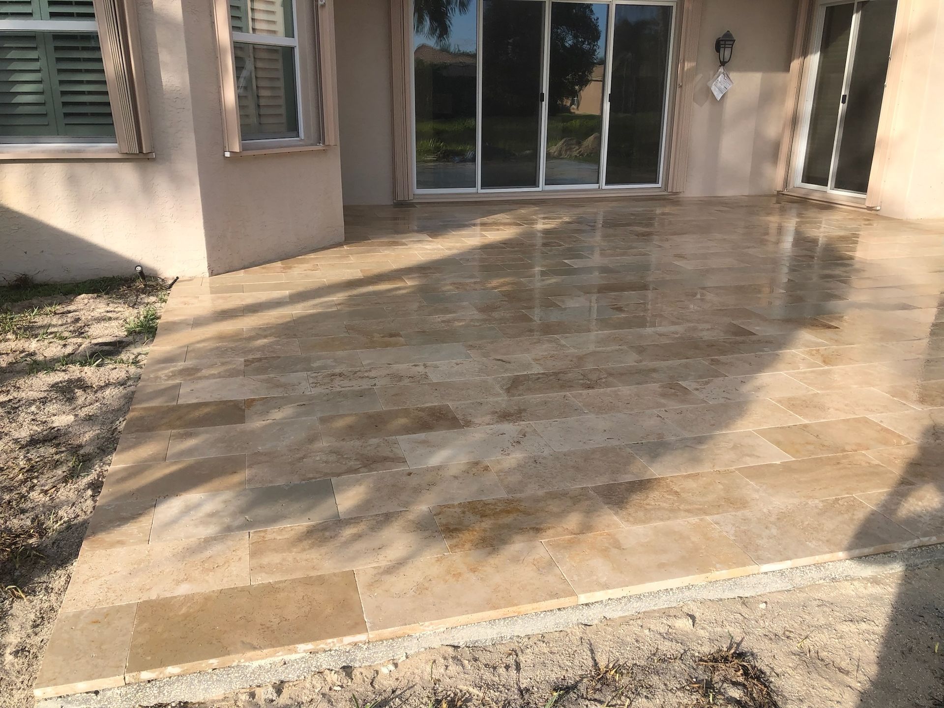 A patio with tiles and a sliding glass door in front of a house.