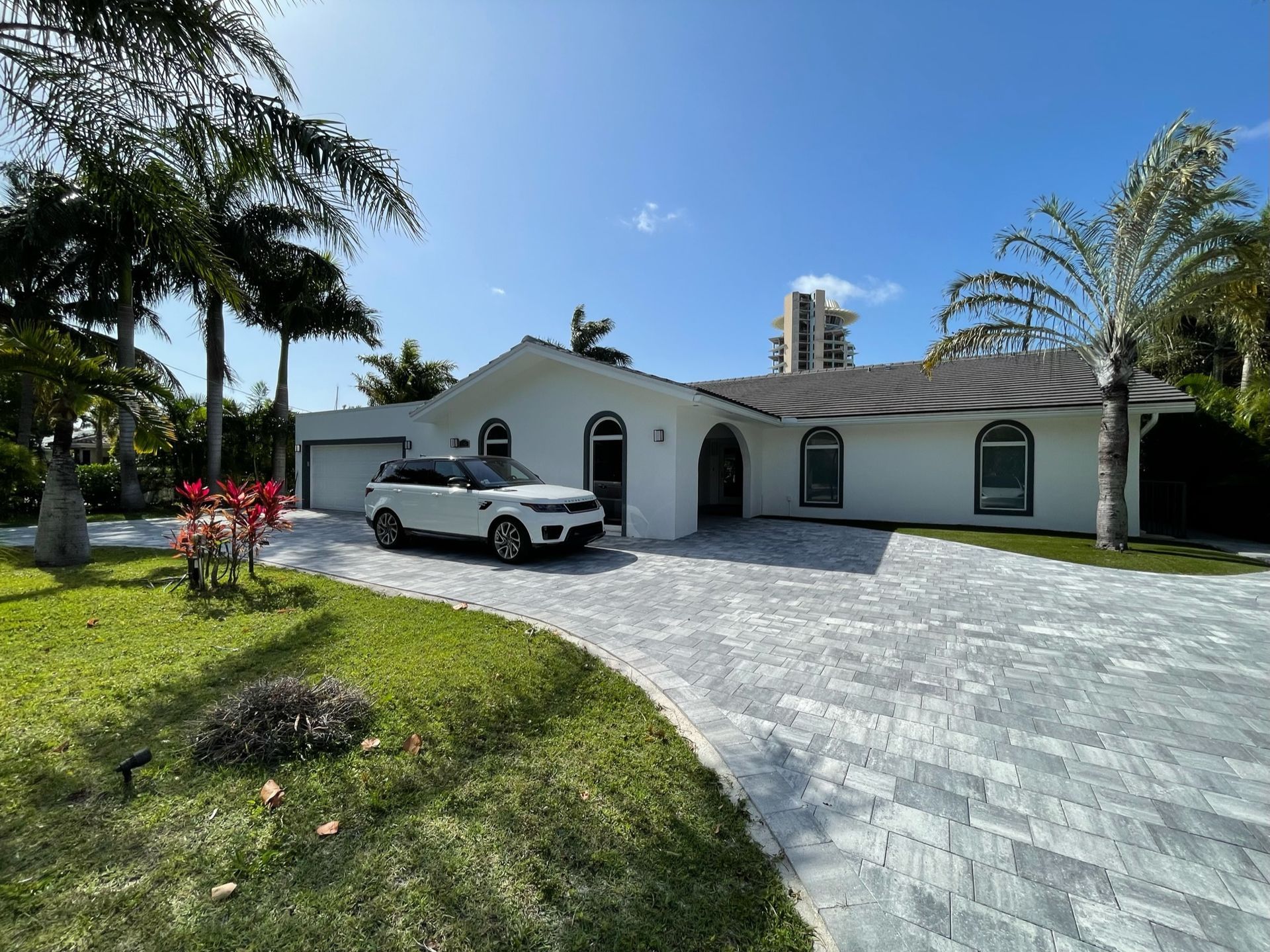 A white suv is parked in front of a white house.