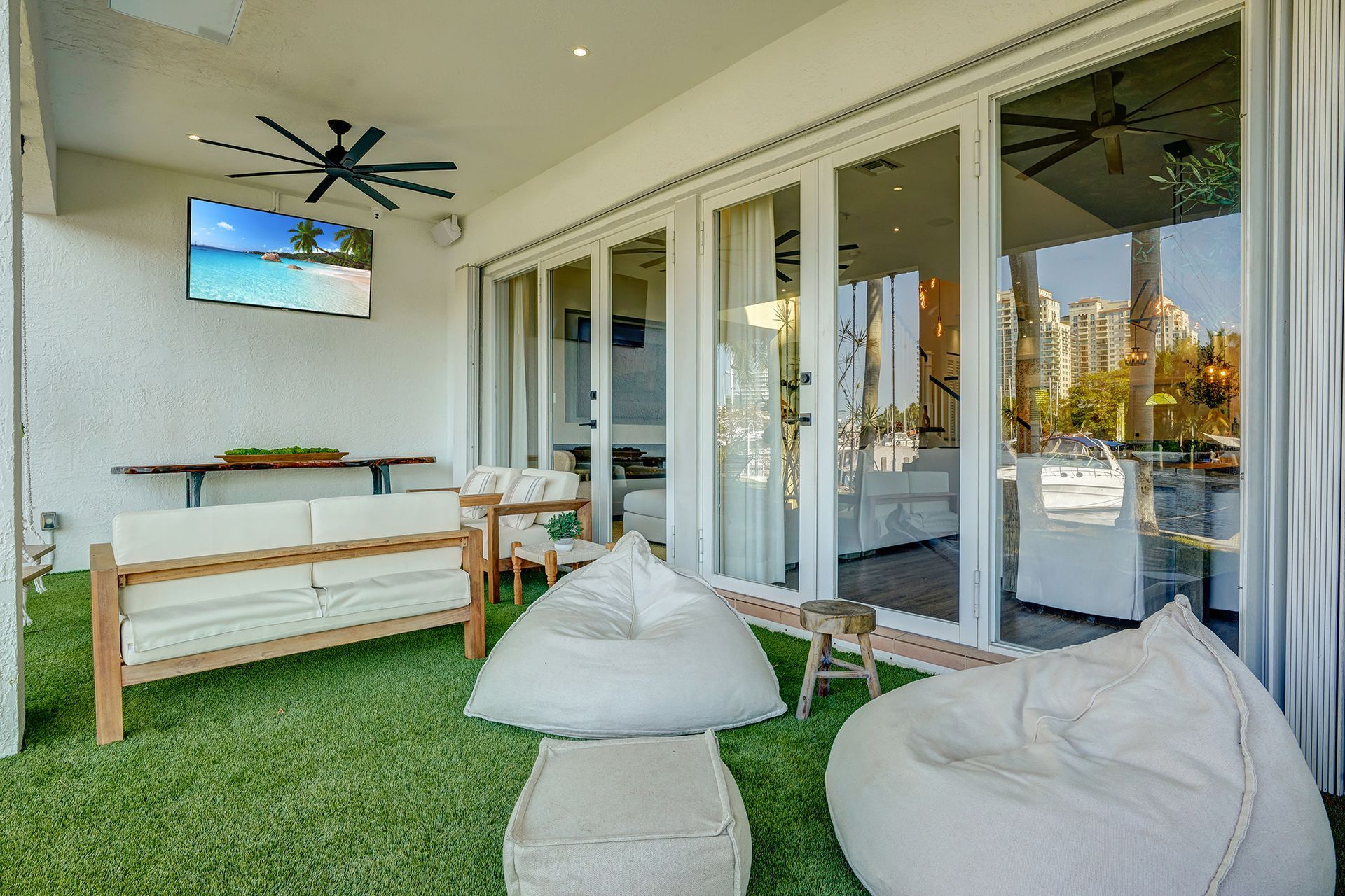 A patio with a couch , chairs , bean bag chairs and a television.