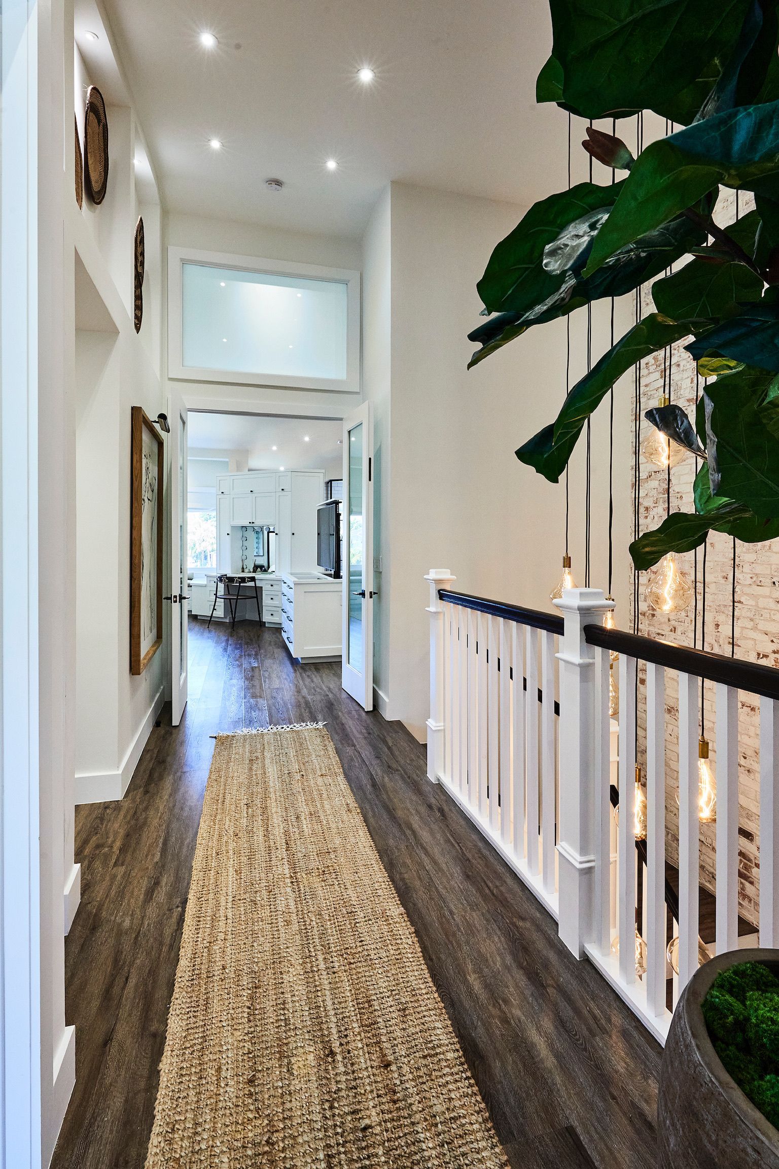 A hallway with a rug on the floor and a plant in the middle.