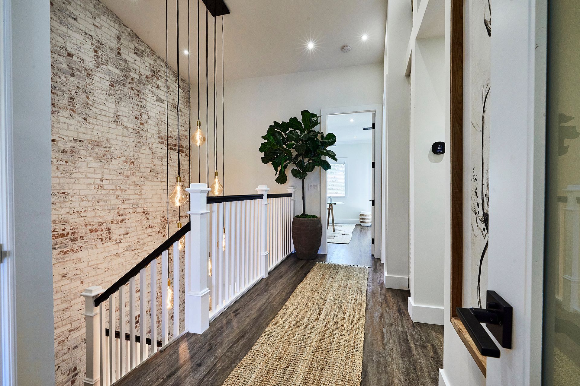 A hallway with a staircase and a plant in a pot.