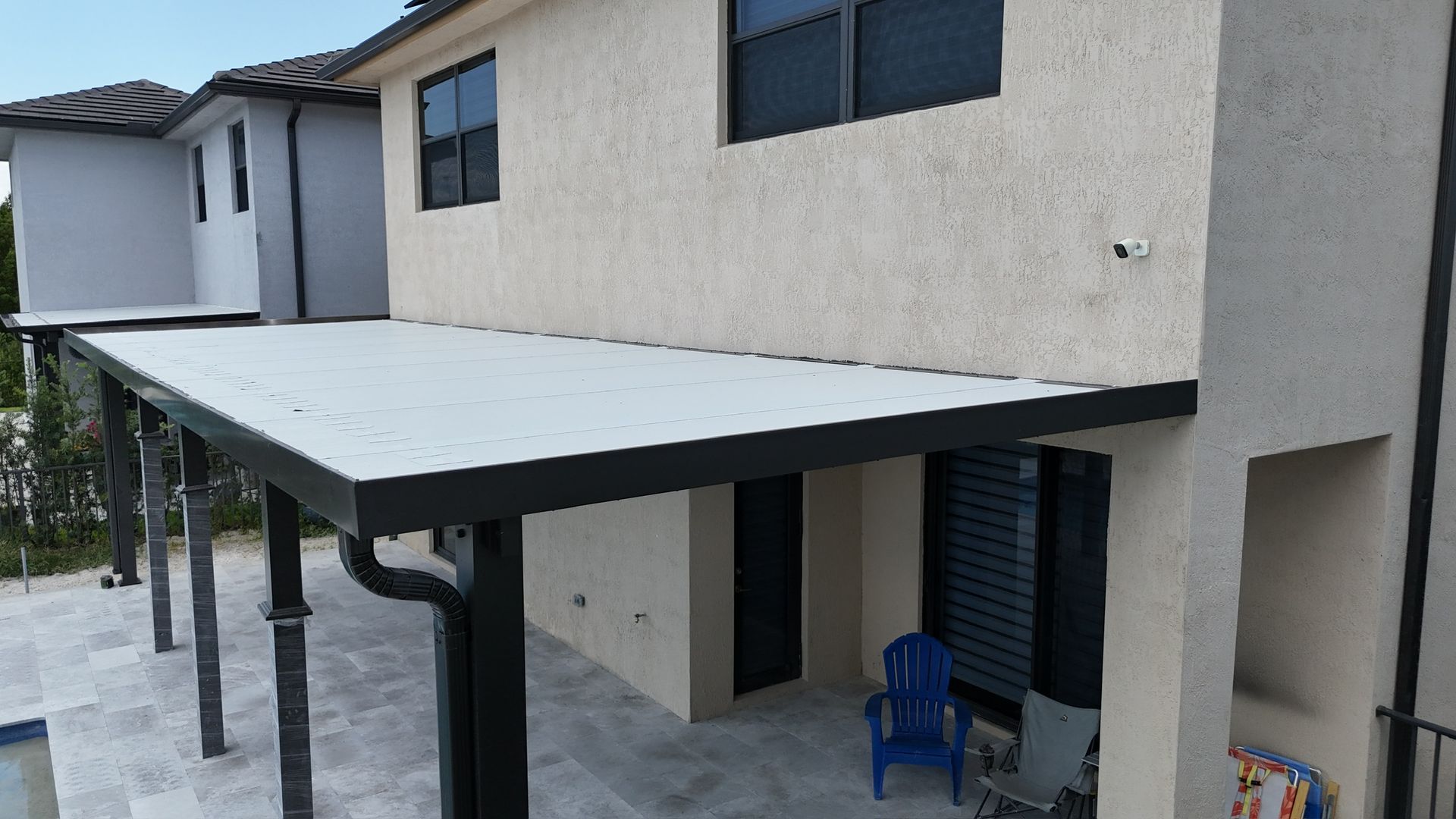 A house with a covered patio and a blue chair on it.