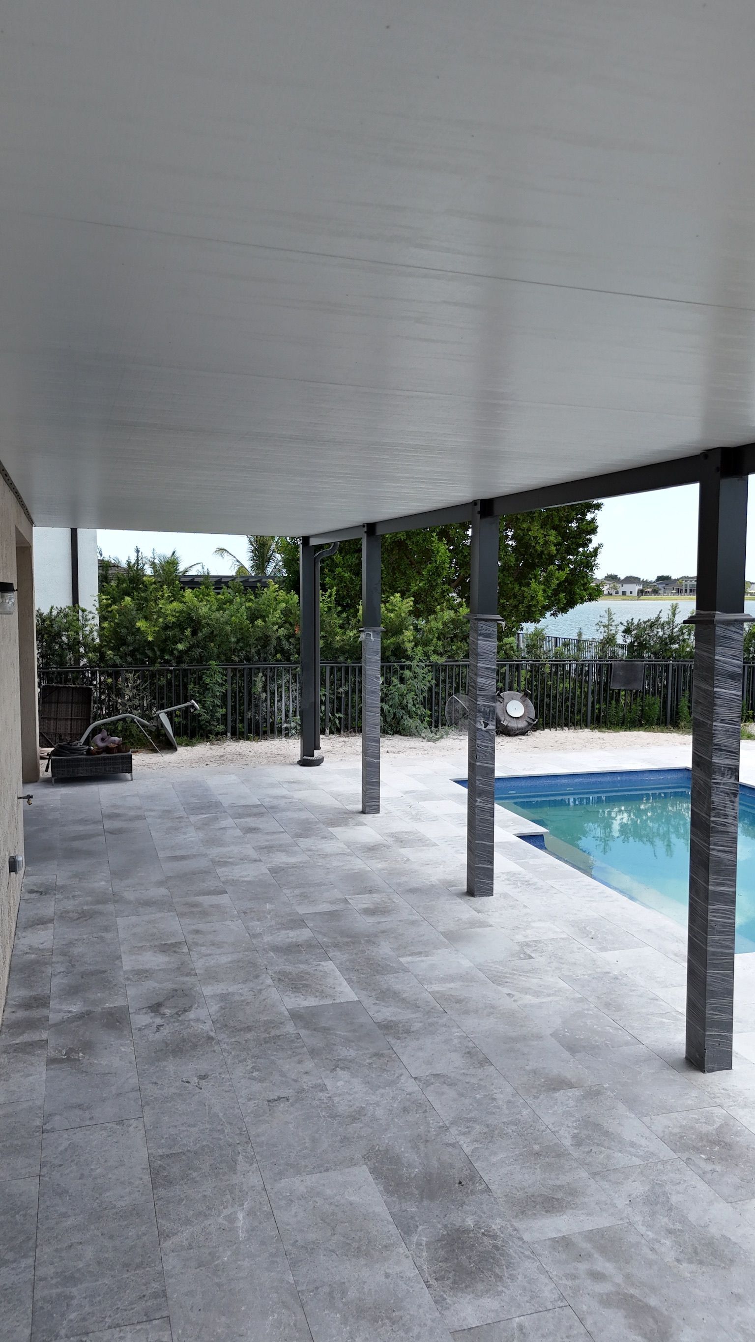 A covered patio with a swimming pool in the background.