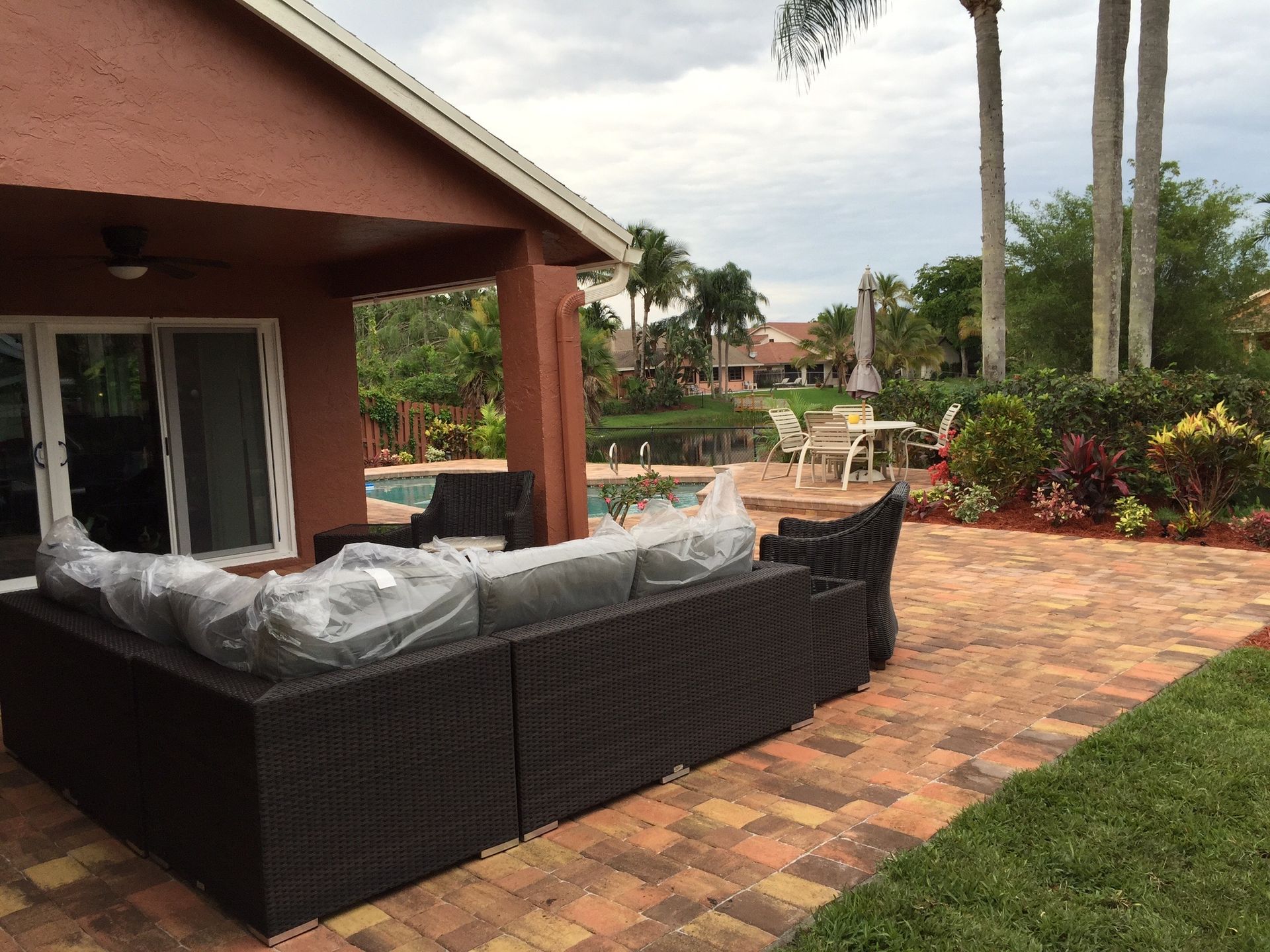A large sectional couch is sitting on a patio in front of a house.