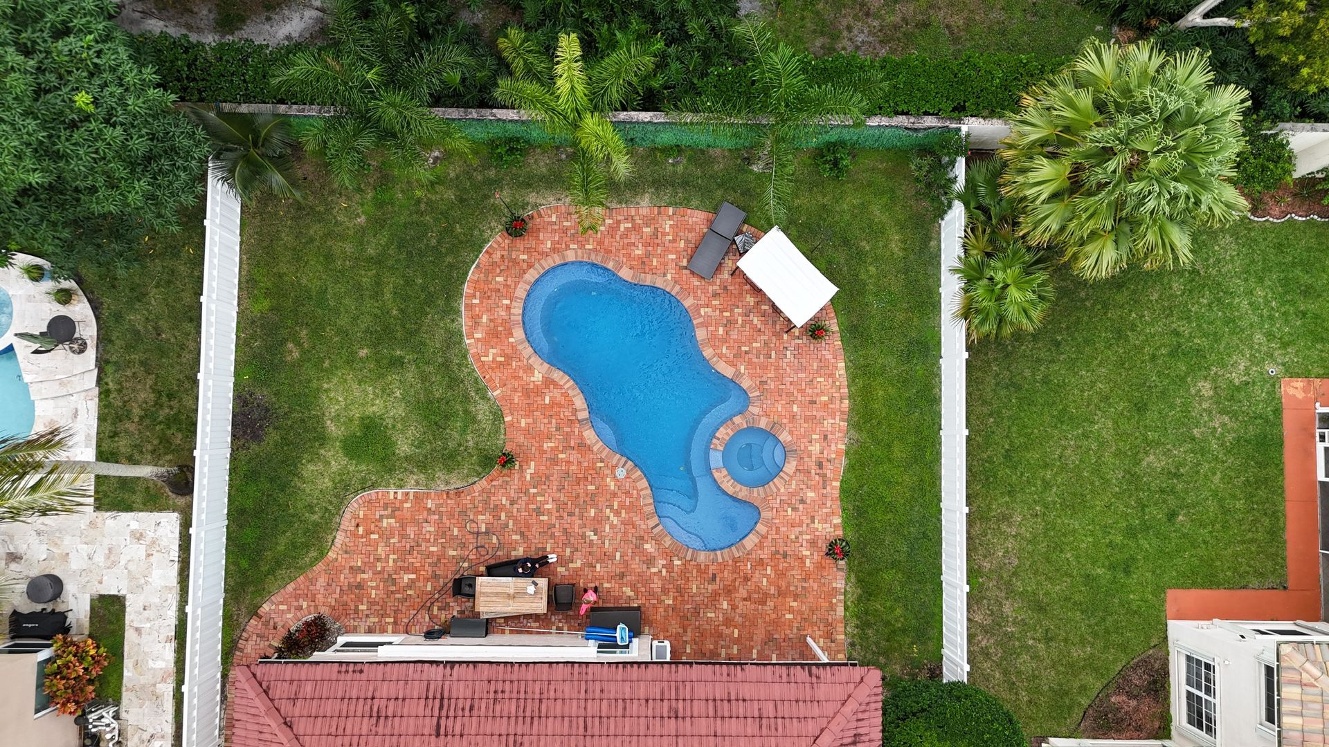 An aerial view of a swimming pool in the backyard of a house.