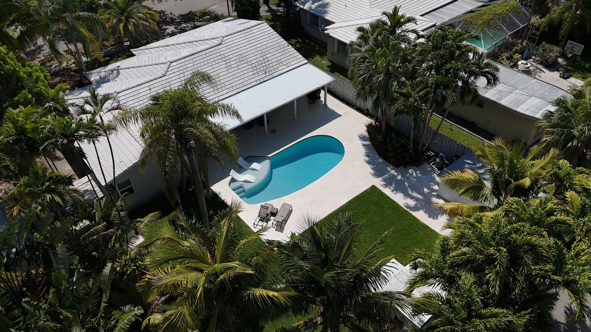 An aerial view of a house with a pool in the backyard surrounded by palm trees.