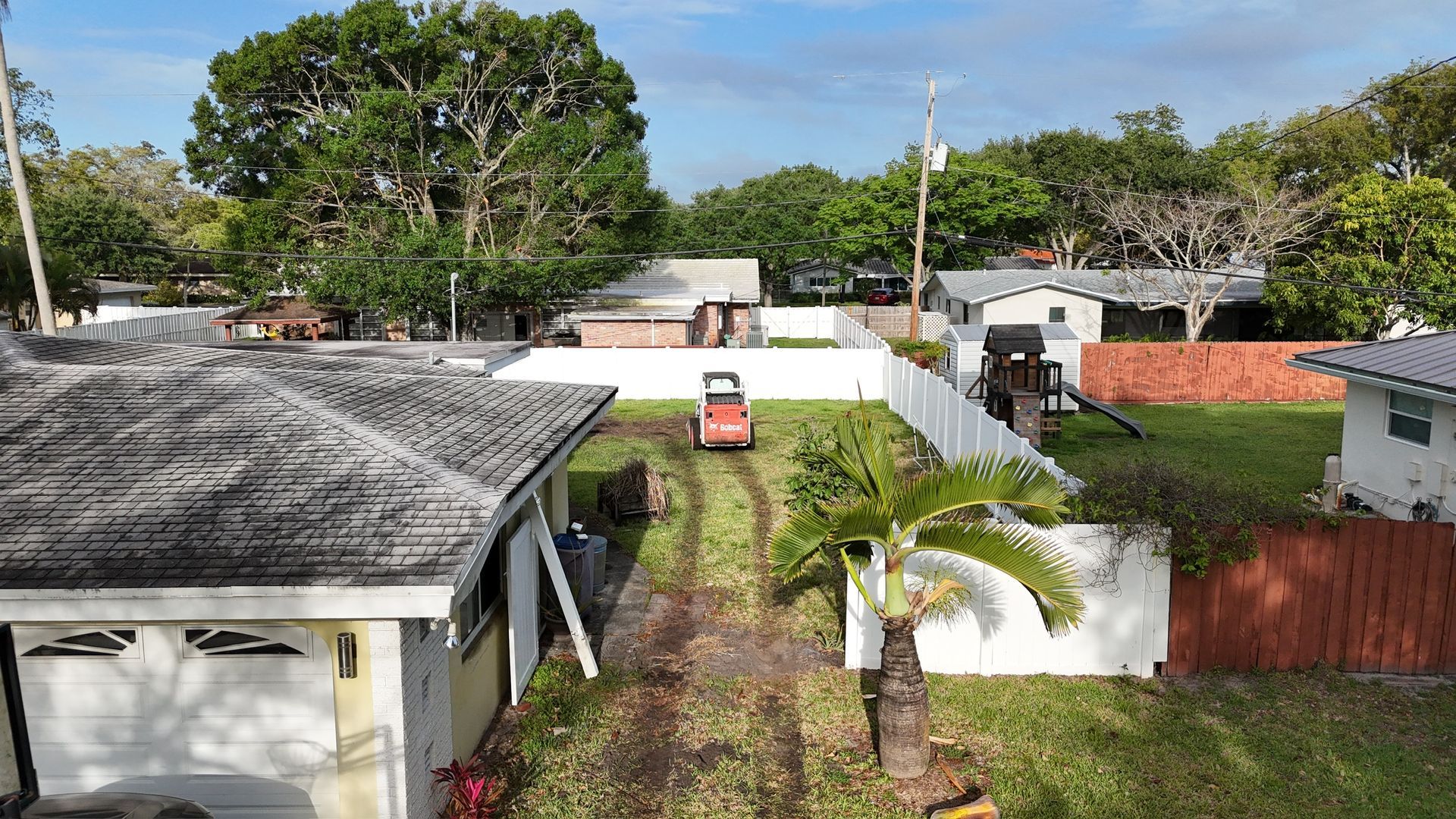 An aerial view of a house with a lawn mower in the backyard.