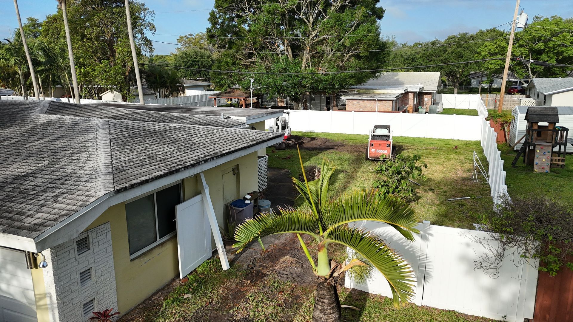 An aerial view of a house with a lawn mower in the backyard.