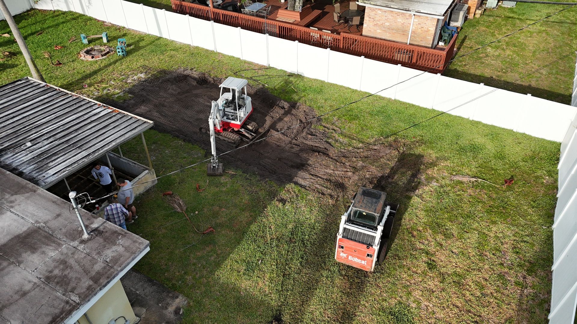 An aerial view of a house with a bulldozer digging a hole in the yard.