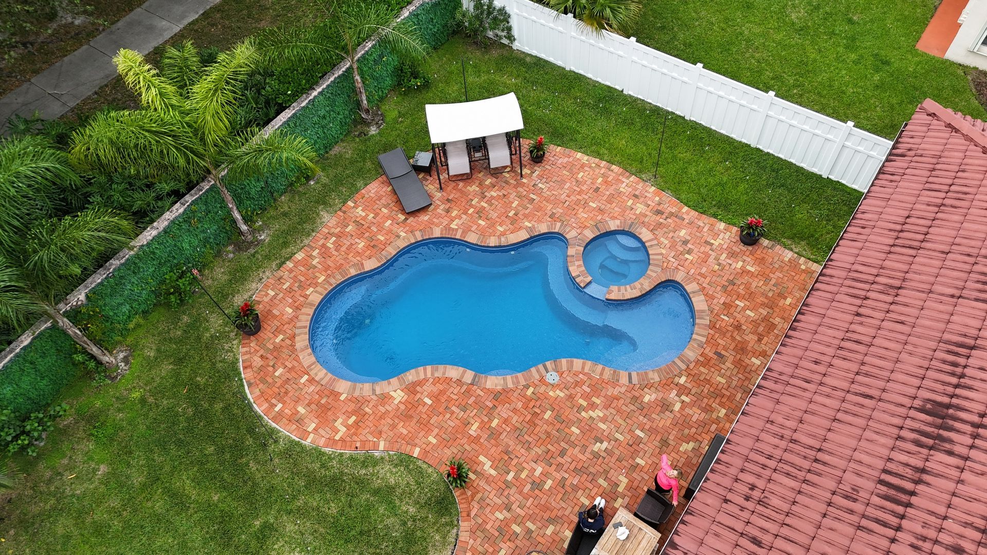 An aerial view of a swimming pool in the backyard of a house.